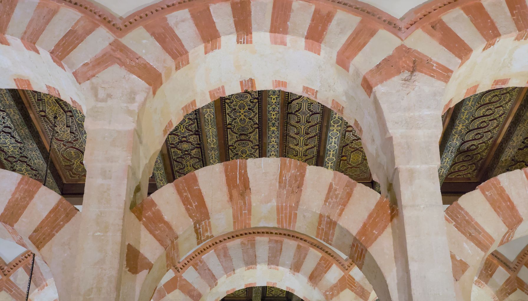 The tiered horseshoe arches of the Mezquita-Catedral of Córdoba, built in alternating brick and stone under a painted timber ceiling.