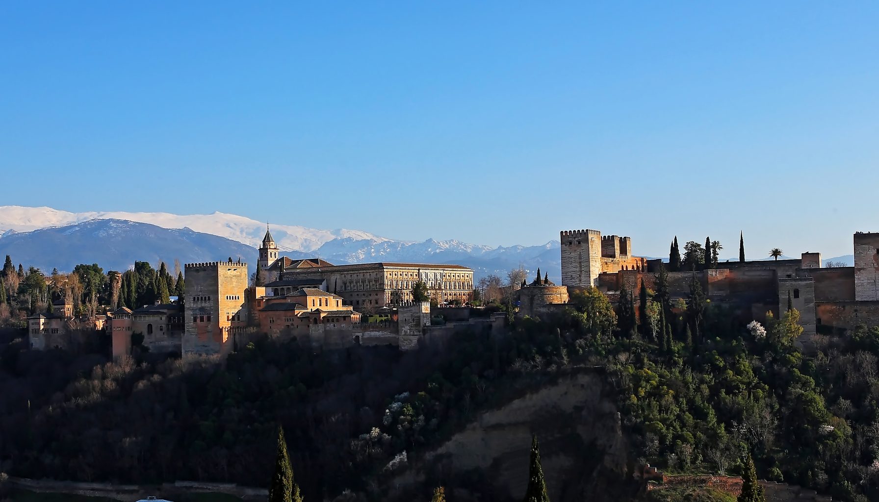 The Alhambra on its ridge above Granada, with the snows of the Sierra Nevada behind it.