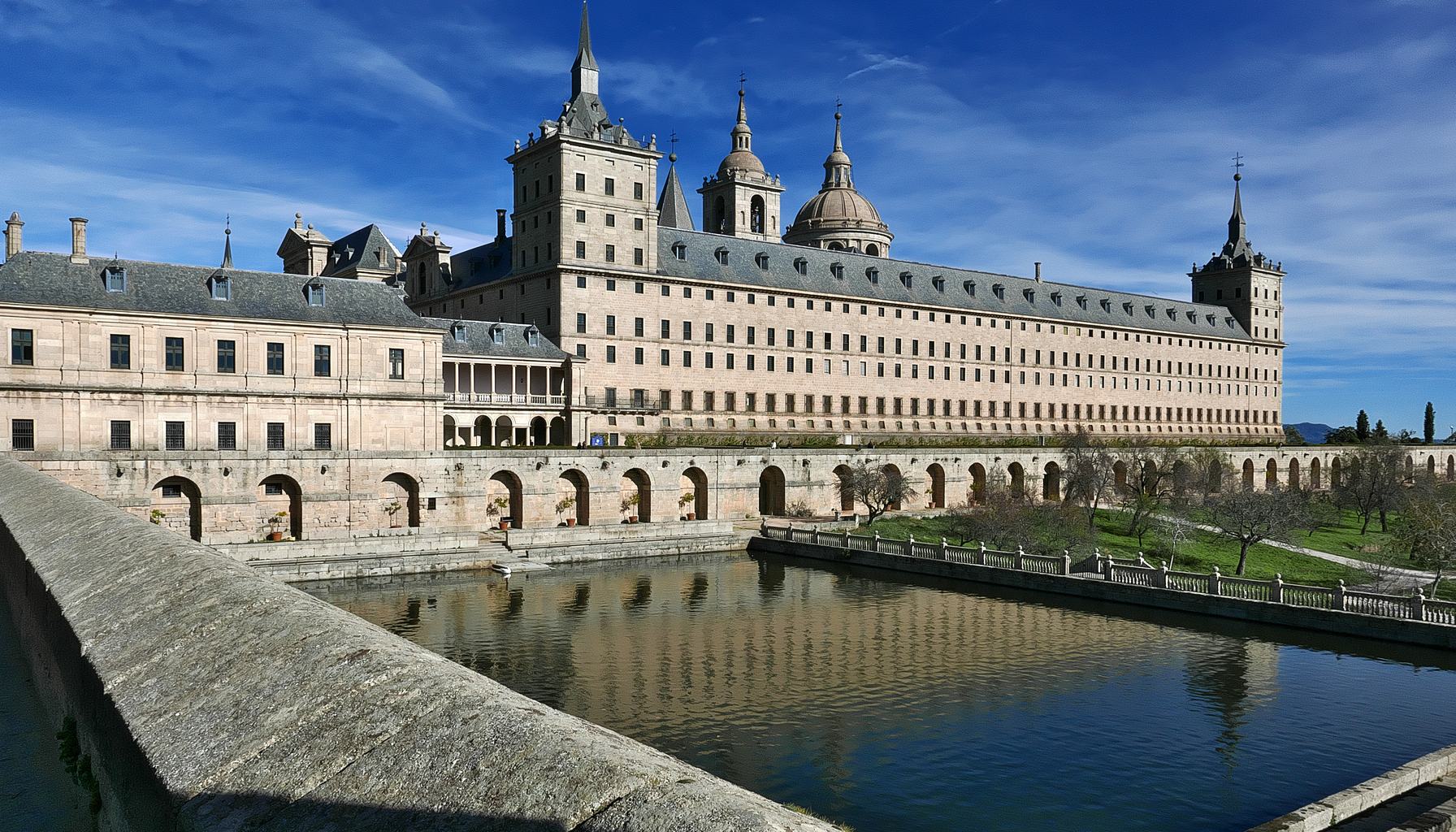 El Escorial seen from the south, across the water of its reservoir.