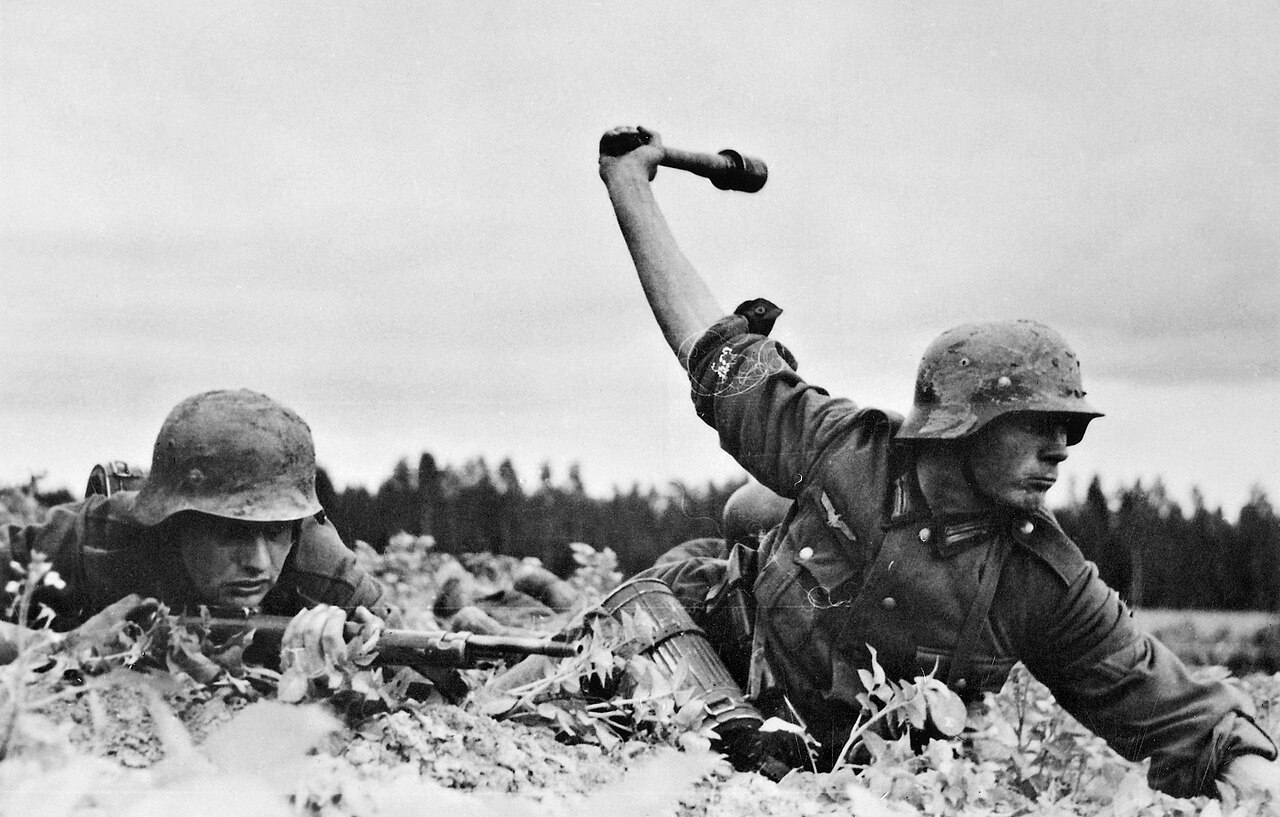Black and white photograph of Allied soldiers landing on a beach under fire during the Normandy landings, June 1944.
